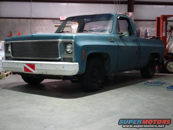 Blue pickup truck with white bumper and dive flag sticker, parked indoors