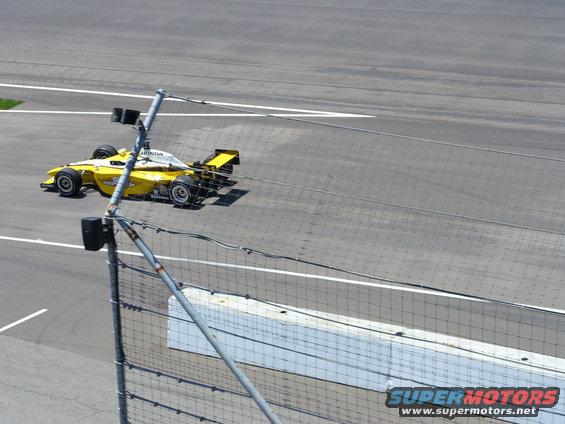 Yellow and white race car on track, rear spoiler visible