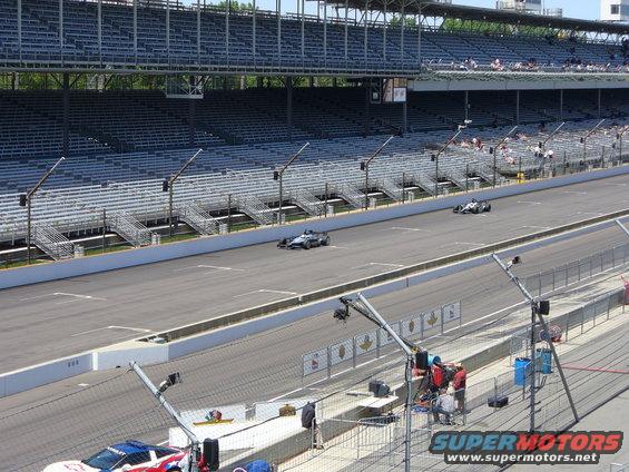 IndyCars race on a track with grandstands