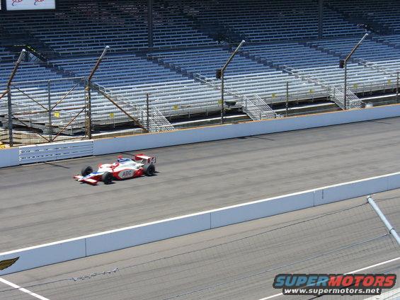 Race car with ABC logo on track in front of empty grandstands