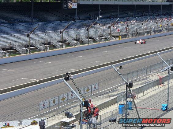 White and red IndyCar on race track with empty grandstands