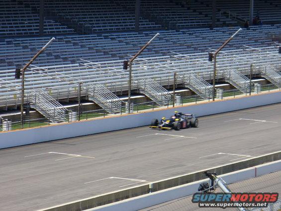 Black and yellow race car on track, front-left view