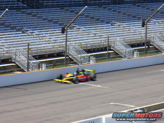 Open-wheel race car with red body and yellow/green accents on track