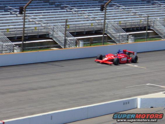 Red race car with CURB text on side, on track