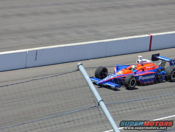 IndyCar race car with blue and orange livery, sponsored by Panasonic, on a track