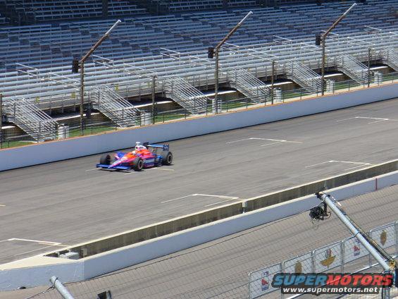 IndyCar race car on track with empty grandstands in background
