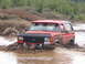 1989 Ford Bronco - A red Ford Bronco navigates a muddy off-road course, its license plate reading GOTPLFX.