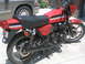 1981 Kawasaki Bayou - A red motorcycle with black seat and distinctive silver and black stripes on the tank and tail section is parked outdoors.