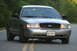 2004 Ford Crown Victoria - This 2004 Ford Crown Victoria is shown from the front on a paved road with yellow lines.