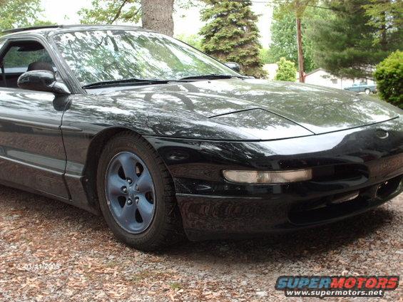 Black Ford Probe with blue wheels, front 3/4 view, parked on gravel