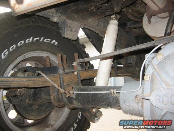 Underneath view of a vehicle's rear axle, leaf springs, and shock absorber. Tire has 'Goodrich' lettering