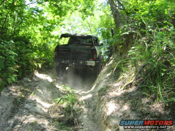 Dark SUV kicking up dust on a steep, wooded trail