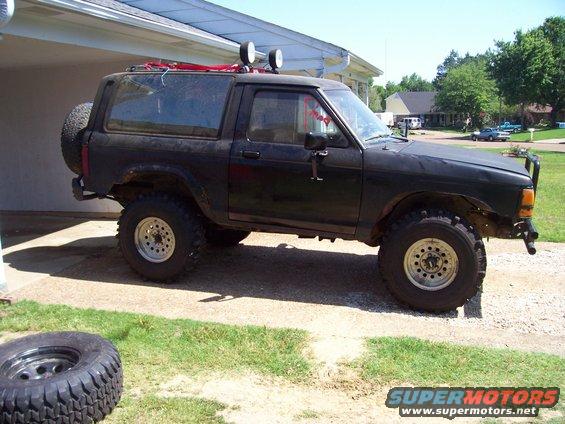 1989 Ford Bronco II with off-road tires and roof lights parked outside a house