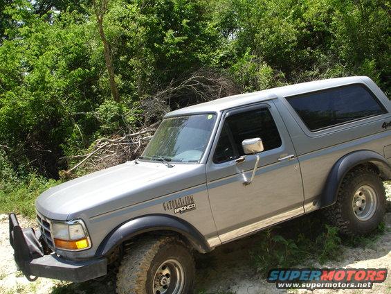 Silver Ford Bronco parked on dirt road with trees in background. Has 'GATOR NATION BRONCO' text on fender