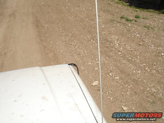 White 1989 Ford Bronco hood and antenna on a dirt road