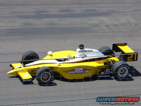 Yellow and white IndyCar with Honda branding and the number 21 on the rear wing