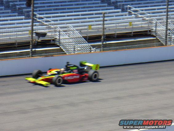 Red and yellow open-wheel race car with green accents on track