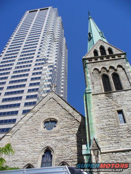 Church steeple and modern skyscraper against blue sky