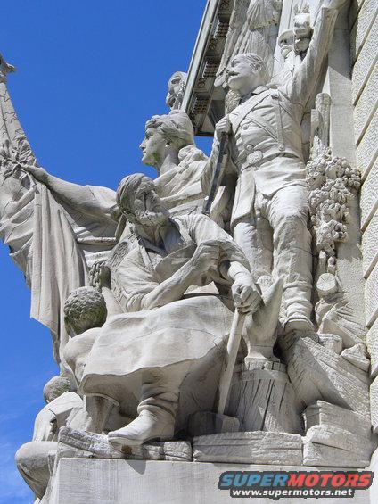 stone sculpture with figures holding a flag and tools