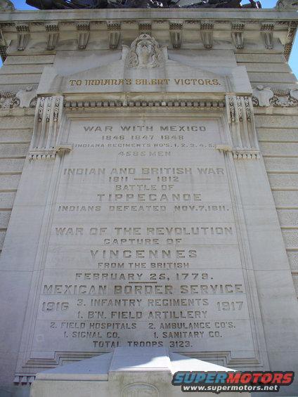 Stone monument with carved text detailing historical wars and troop numbers