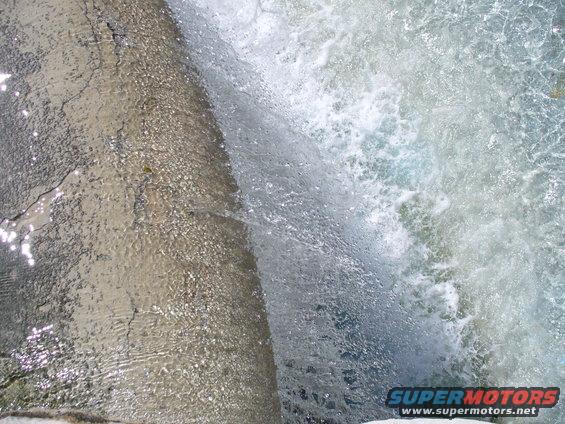 Waterfall cascading over cracked concrete with Supermotors.net logo