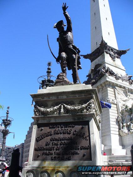 Monument with statue of George Rogers Clark and inscription, under a blue sky
