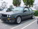 1989 BMW 3 Series - A dark green 1989 BMW 3 Series coupe is parked in a lot, showing its distinctive front grille and alloy wheels.