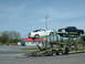 2007 Ford Mustang - Car carrier transporting a white Mustang convertible and a black pickup truck under a blue sky.