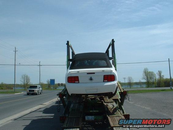 White convertible car on a car hauler, another SUV on the road ahead