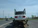 2007 Ford Mustang - A white convertible is being transported on a car hauler, with another vehicle visible on the road.