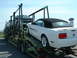 2007 Ford Mustang - Multiple vehicles are transported on a car carrier, including a white convertible Ford Mustang.