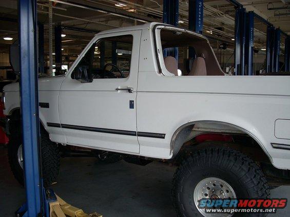 1992 Ford Bronco side view, lifted and in a repair shop with a lift