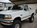 1992 Ford Bronco - This lifted 1992 Ford Bronco is parked under a covered area, with another vehicle partially visible behind it.