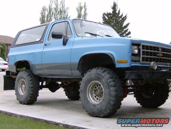 Lifted blue SUV with large tires parked on a driveway. Text on windshield reads 'Soul Survivor'
