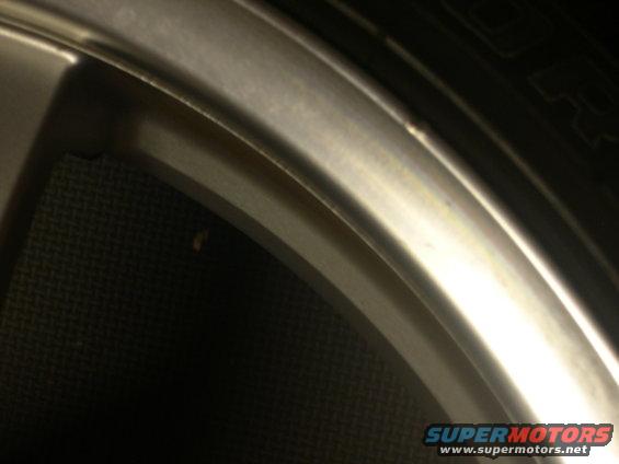 Close-up of a vehicle's alloy wheel and tire with a "Supermotors.net" watermark