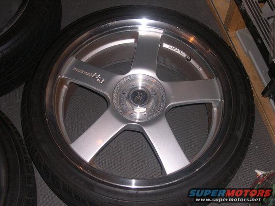 Close-up of a silver five-spoke aftermarket wheel with a tire mounted