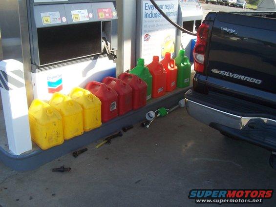 Black Chevrolet Silverado pickup truck rear view at gas station with gas cans