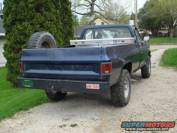Blue pickup truck, spare tire in bed, toolbox, aftermarket bumper, Wisconsin plate