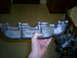2003 Mercury Marauder - A hand holds an exhaust manifold, showing Ford branding and part numbers visible on the casting.