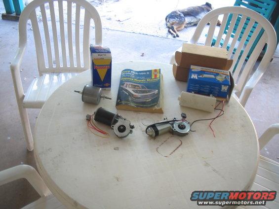 Two electric motors, a fuel filter, and a Ford Pick-ups & Bronco Haynes Repair Manual sit on a round table