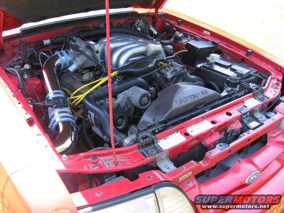 Red engine bay with chrome intake, "CAUTION FAN" shroud, and "SUPERMOTORS" watermark
