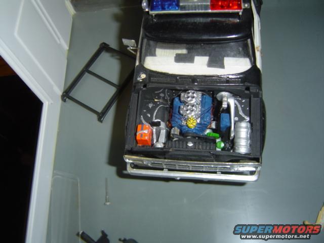 Model police car with hood open showing engine detail, blue engine block, chrome air intake