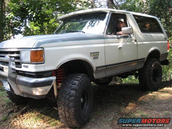 White Ford Bronco with lifted suspension and off-road tires on a dirt trail