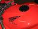 2002 Honda Interceptor - A close-up view of a red motorcycle's fuel tank, adorned with a Honda wing emblem and a gas cap, with racing gloves placed on top.