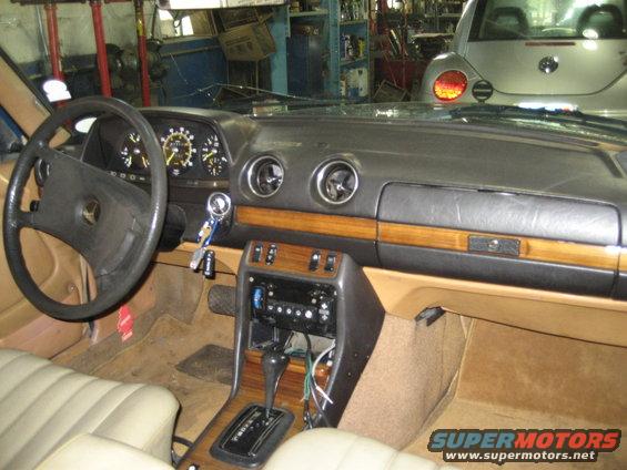 Interior shot of a car with a wood-grain dash, automatic shifter, and a Volkswagen Beetle visible through the windshield
