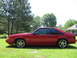 1967 Ford Mustang - Side view of a red 1993 Ford Mustang coupe with a "5.0" badge, parked on a grassy lawn.