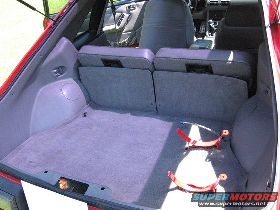 Red hatchback interior showing folded rear seats and carpeted cargo area with red brackets