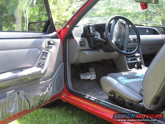 Interior of a red car, showing the driver's seat, dashboard, steering wheel, and door panel