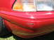 1967 Ford Mustang - The front corner of a red car shows damage to the bumper and fender area.