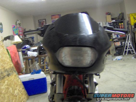 Motorcycle front fairing with a black windscreen and a large headlight. The bike is in a garage setting